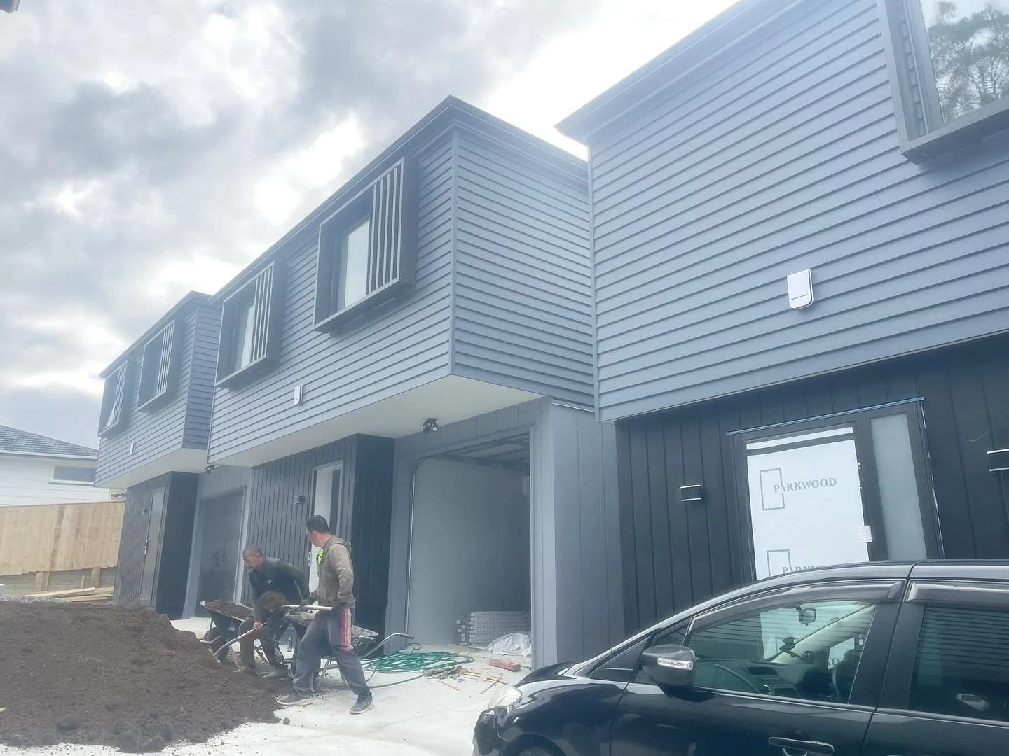 Two-storey townhouse exterior with dark weatherboards and light trim