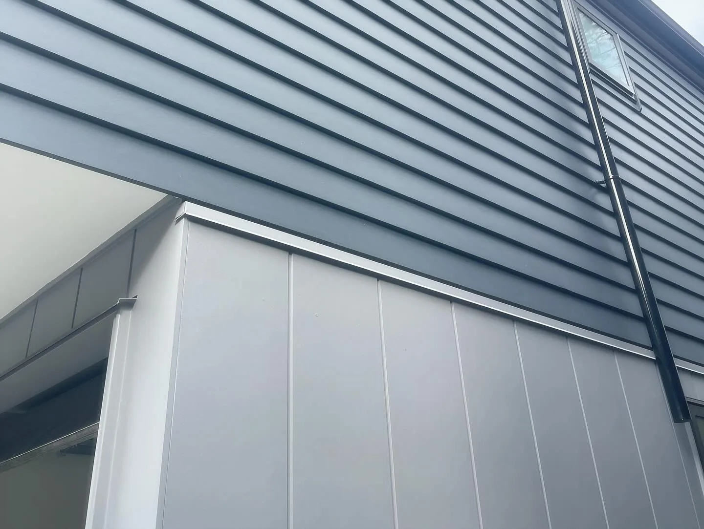 Close view of dark horizontal exterior cladding and light vertical panels